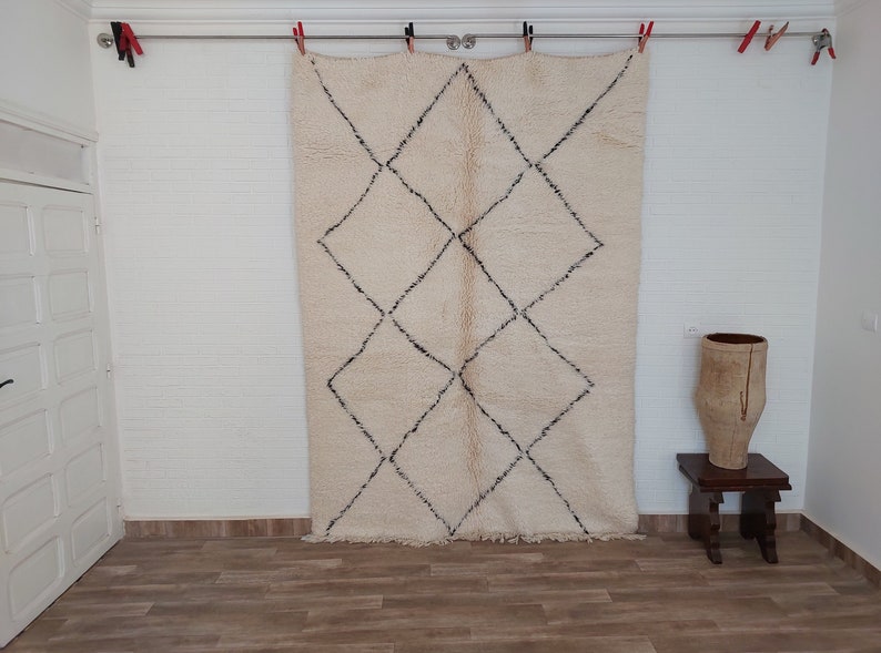Authentic Beni Ourain Moroccan rug in cream handwoven wool with black diamond lattice, fringed edges on a 5x9 area rug.