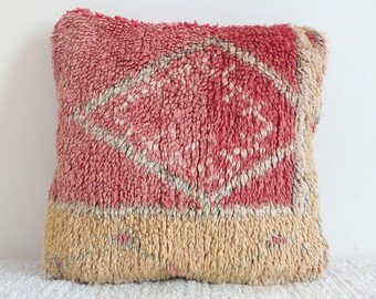 Può includere: Un cuscino quadrato e strutturato con un design geometrico rosso e beige. Il cuscino ha una consistenza lanuginosa e tessuta e una combinazione di colori a due toni, con un motivo centrale rosso e un bordo inferiore beige. Per l'arredamento della casa.