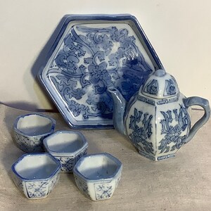 May include: A blue and white porcelain tea set with a hexagonal tray, teapot, and four cups. The set features a floral design.