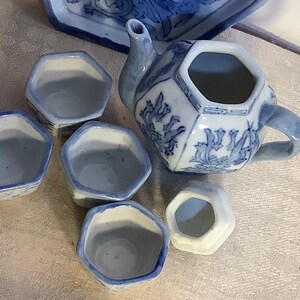 May include: A blue and white porcelain tea set with a teapot and four cups. The teapot and cups have a floral design.