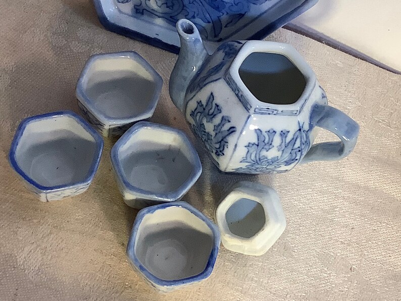 May include: A blue and white porcelain tea set with a teapot and four cups. The teapot and cups have a floral design.