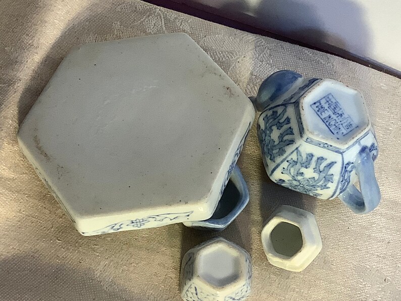 May include: A blue and white porcelain tea set with a hexagonal teapot, creamer, sugar bowl, and a hexagonal tray. The teapot has a handle and a spout. The tray has a floral design.