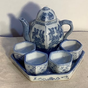 May include: A blue and white porcelain tea set with a teapot and four cups on a matching tray. The set features a floral design.