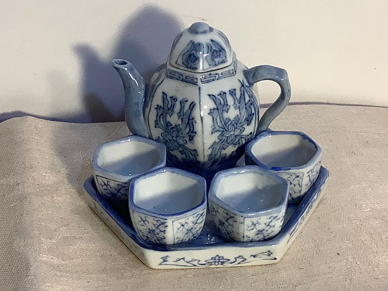 May include: A blue and white porcelain tea set with a teapot and four cups on a matching tray. The set features a floral design.