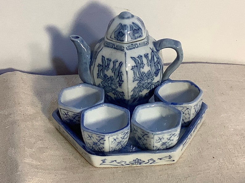 May include: A blue and white porcelain tea set with a teapot and four cups. The set features a floral design and is perfect for a traditional tea ceremony.