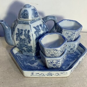 May include: A blue and white porcelain tea set with a teapot, four cups, and a tray. The set features a floral design.