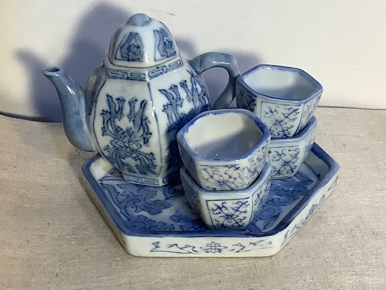 May include: A blue and white porcelain tea set with a teapot, four cups, and a tray. The set features a floral design.