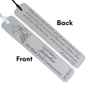 May include: Silver bookmark with a cross and grapes on the front. The back has a religious quote and the text "God Bless Jacqueline On Your First Communion 05.06.23".