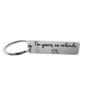 May include: A silver-colored rectangular keychain with a key ring. The keychain has the phrase "I'm yours, no refunds" engraved on it, along with a heart symbol. The text and heart are in black.