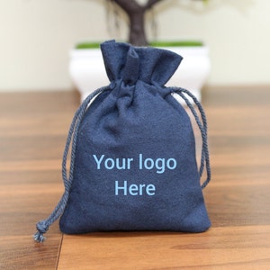 Könnte beinhalten: Eine dunkelblaue Kordeltasche aus Stoff mit dem Aufdruck "Your logo Here" auf der Vorderseite.
