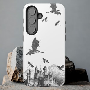 Könnte beinhalten: Weißes Handy-Case mit einem schwarzen Kameraobjektiv und einem Design eines Schlosses mit Drachen, die herumfliegen.