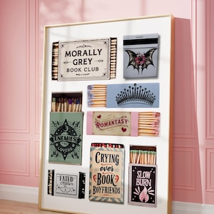 May include: A framed display of matchboxes with various designs and text. The matchboxes feature phrases like "Morally Grey Book Club," "Enemies to Lovers," and "Crying Over Book Boyfriends." The color palette includes pink, blue, and green.