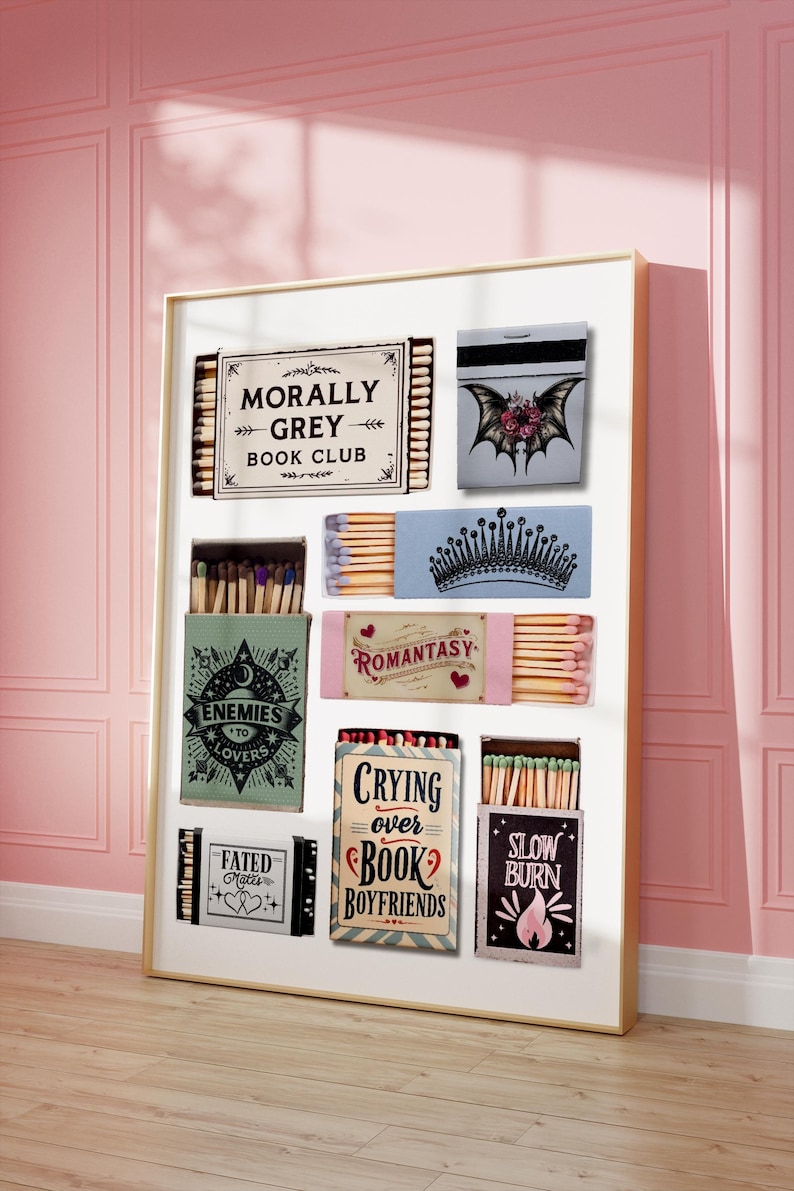 May include: A framed display of matchboxes with various designs and text. The matchboxes feature phrases like "Morally Grey Book Club," "Enemies to Lovers," and "Crying Over Book Boyfriends." The color palette includes pink, blue, and green.