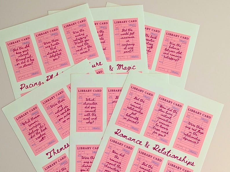 May include: A collection of pink library cards with handwritten questions on a light green background. The cards are grouped together, with titles like "Pacing, Plot" and "Romance & Relationships" in cursive.