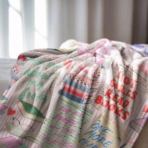 May include: A soft, white blanket with a colorful book-themed design. The blanket features text like "Ask me about my books" and "Hot girls read books" in various fonts and colors, along with book illustrations and library card designs.