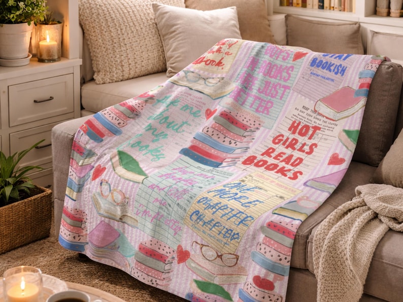 May include: A soft, light pink throw blanket with a collage of book-themed graphics. The blanket features stacks of books, glasses, and text that reads "Hot Girls Read Books" and "Stay Bookish".