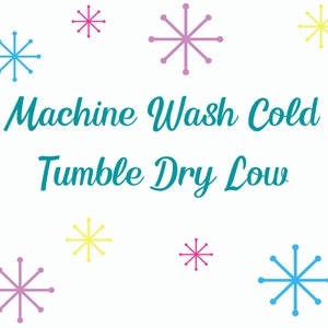 May include: A white background with the text "Machine Wash Cold Tumble Dry Low" in teal blue.  There are nine snowflakes in various colors, including pink, blue, and yellow.