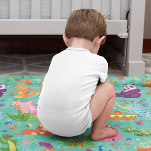 May include: A baby sitting on a colorful play mat with a jungle animal theme. The mat features a variety of animals, including a lion, a giraffe, a panda, and a monkey. The mat is made of soft, plush fabric and is perfect for babies and toddlers.