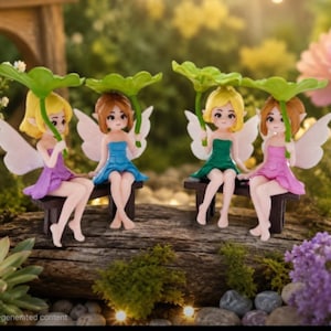 Puede incluir: Cuatro figuras de hadas en miniatura con cabello rubio, castaño y amarillo, vestidas con vestidos coloridos y sosteniendo paraguas de hojas verdes. Están sentadas en un pequeño banco de madera, con alas blancas, en un jardín.