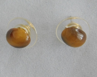 Könnte beinhalten: Ein Paar goldfarbene Ohrstecker mit Tigeraugen-Steinen, die in klarem Kunststoff gefasst sind.