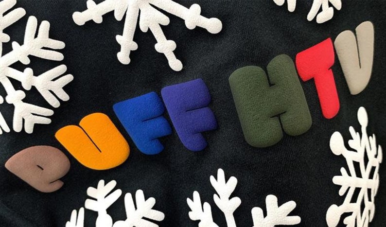 May include: A black sweatshirt with the words "PUFF HTV" in colorful, puffy letters. The letters are in different colors, including brown, orange, blue, purple, green, and red. The sweatshirt is decorated with white snowflake designs.