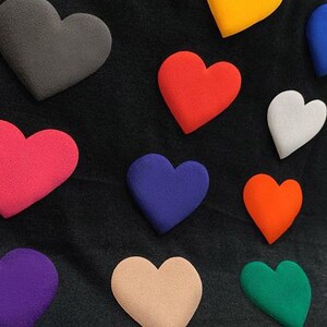 May include: A black fabric background with ten colorful felt hearts in various shades of red, pink, purple, blue, green, orange, yellow, and gray.