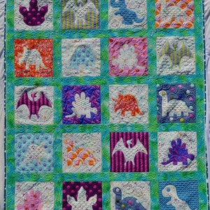 May include: A colorful quilt with a dinosaur theme. The quilt is made up of 16 squares, each with a different dinosaur design. The dinosaurs are all different colors and have different patterns. The quilt is perfect for a child's room or nursery.
