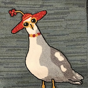 May include: A whimsical rug depicting a cartoon seagull wearing a red hat with a yellow band and a red flower. The seagull has large, round eyes and a white body with gray wings and a gray tail. The seagull is standing on a blue and green background.