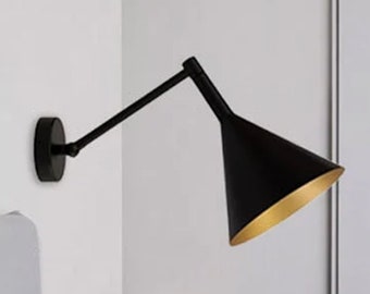 May include: Black wall-mounted light fixture with a gold-accented, adjustable, cone-shaped shade.