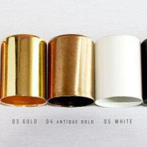 May include: Seven different colored metal bottle stoppers, from left to right: chrome, copper, gold, antique gold, white, black, and emerald.