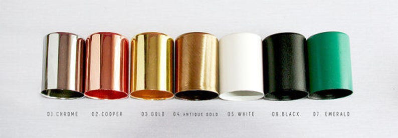 May include: Seven different colored metal bottle stoppers, from left to right: chrome, copper, gold, antique gold, white, black, and emerald.