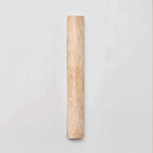 May include: A light beige, rectangular, stone-like object with a slightly textured surface. The object is a long, narrow column with a rounded end. The column is set against a white background.