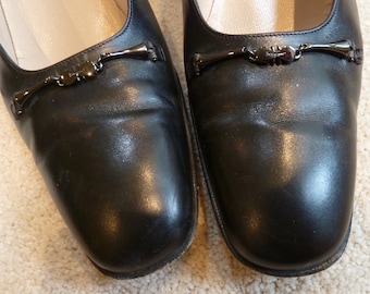 May include: A pair of black leather women's flats with a silver buckle detail.