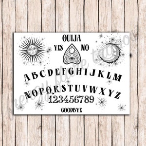 K&ouml;nnte beinhalten: Ein schwarz-wei&szlig;es Ouija-Brett mit den Buchstaben des Alphabets, den Zahlen 1-9 und den W&ouml;rtern "YES", "NO", "GOODBYE" und "OUIJA". Das Brett ist mit einer Sonne, einem Mond und einem Planchette mit einem Auge verziert.