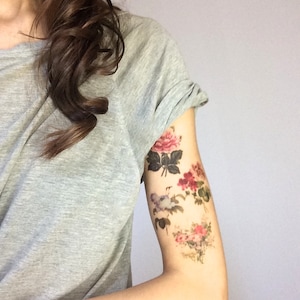 K&ouml;nnte beinhalten: Nahaufnahme eines Arms mit einem floralen tempor&auml;ren Tattoo. Das Tattoo zeigt rosa, rote und wei&szlig;e Blumen mit gr&uuml;nen Bl&auml;ttern.