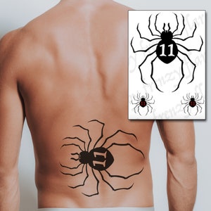 Puede incluir: Tatuaje temporal de araña negra con el número 11 en el abdomen, mostrado en la espalda de una persona. La imagen también muestra una hoja con diseños de arañas, incluido el número 11 en rojo.