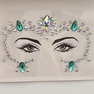 May include: A face jewel sticker set with iridescent and green rhinestones. The sticker set includes a forehead design with a pearl in the center, and two eye designs with a larger green rhinestone on each side.