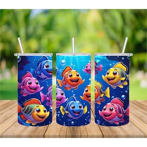 Puede incluir: Tres vasos de acero inoxidable con diseños de peces de dibujos animados coloridos. Los peces son en tonos de rosa, naranja, amarillo y azul, sobre un fondo submarino azul con burbujas. Cada vaso tiene una pajita blanca.