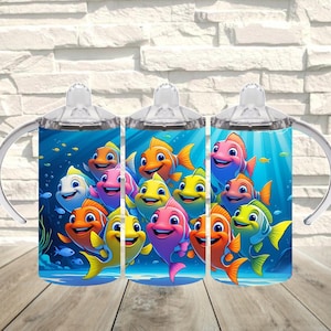 May include: Three baby bottles with handles, each featuring a vibrant underwater scene with colorful cartoon fish. The bottles have clear tops and are set against a light brick background.