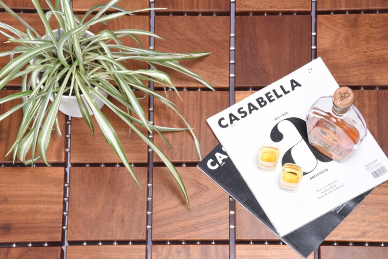 May include: A wooden tile floor with a potted plant, a magazine titled "Casabella", two shot glasses, and a bottle of liquor.