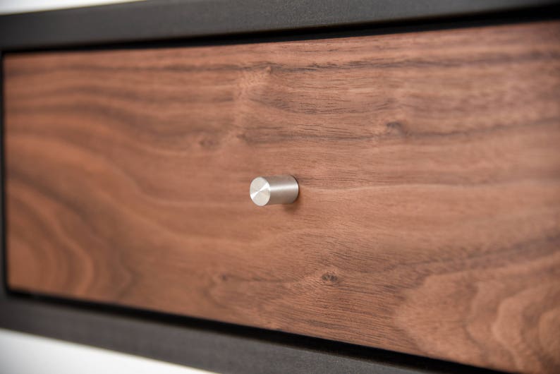May include: Close-up of a wooden drawer with a silver knob. The drawer is made of walnut wood and has a natural finish.