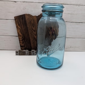 May include: A vintage blue Ball SureSeal mason jar. The jar has a screw-on lid and embossed lettering. The word "Ball" is written in cursive on the front of the jar. The word "vintage" is spelled out in individual metal letter blocks.