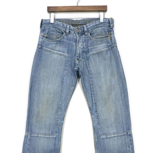 Könnte beinhalten: Hellblaue Jeans aus Denim mit Used-Look und mehreren Nähten. Die Jeans haben eine gerade Passform und einen Knopfverschluss.