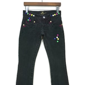 May include: Black denim jeans with colorful square embellishments on the front pockets and waistband. The jeans have a bootcut style.