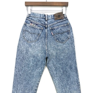 Puede incluir: Un par de pantalones vaqueros de mezclilla azul claro lavados con ácido con un parche de cuero marrón en la parte posterior. El parche tiene el texto "Silver Tab" y "Levi's".