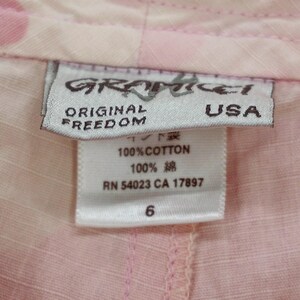 May include: A white tag with pink and black text that reads "Graffiti Original Freedom USA" and "100% Cotton 100% 綿 RN 54023 CA 17897 6".