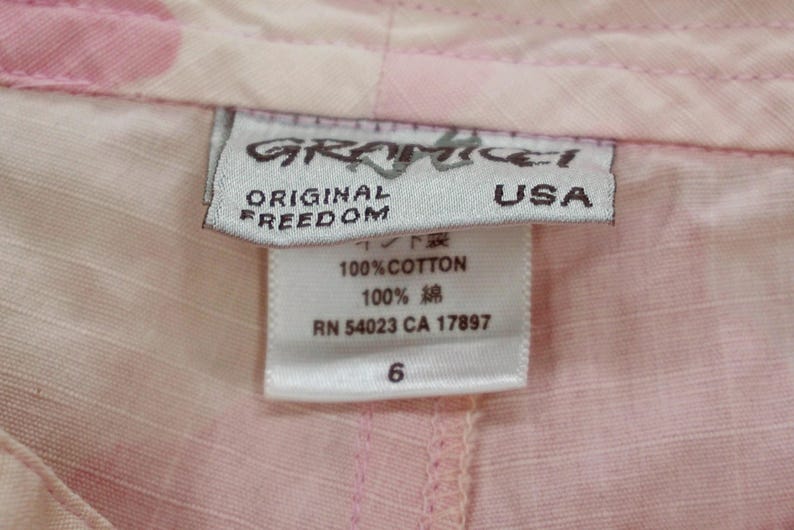 May include: A white tag with pink and black text that reads "Graffiti Original Freedom USA" and "100% Cotton 100% 綿 RN 54023 CA 17897 6".
