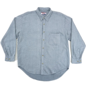 May include: A light blue button-down shirt with long sleeves. The shirt has a chest pocket on the left side and a small logo near the pocket. The collar is buttoned down, and the cuffs have button closures. The shirt is made of a textured fabric.