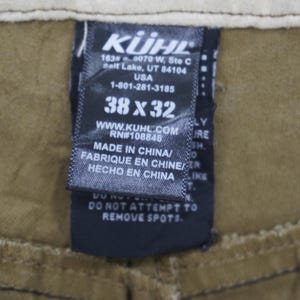 Puede incluir: Una etiqueta en blanco y negro con el nombre de la marca "K&Uuml;HL" y el texto "1634 0070 W, Ste C Salt Lake, UT 84104 USA 1-801-281-3185 38 x 32 WWW.KUHL.COM RN#108846 MADE IN CHINA/ FABRIQUE EN CHINE/ HECHO EN CHINA DO NOT ATTEMPT TO REMOVE SPOTS."