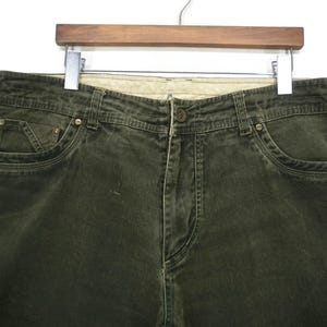 Puede incluir: Un par de pantalones vaqueros de color verde oscuro con un estilo cl&aacute;sico de cinco bolsillos.